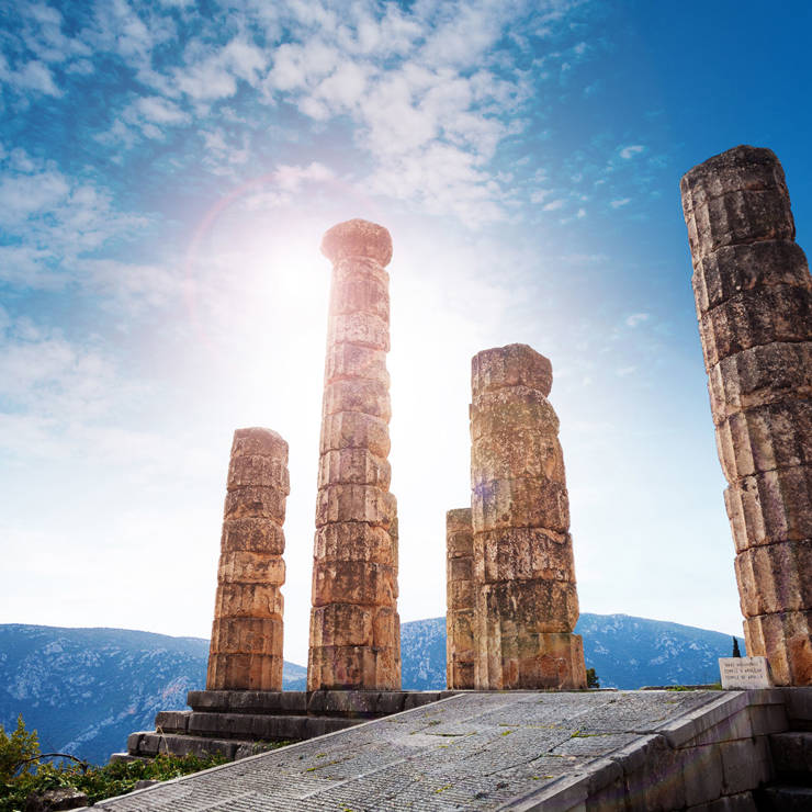 Ancient stone columns of the Temple of Apollo in Delphi under bright sunlight