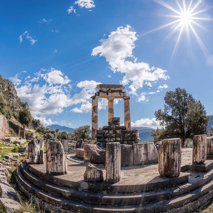 Fisheye view of the Tholos of Delphi with ancient marble columns under a blue sky