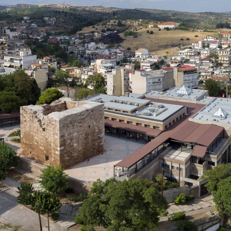 Stone church building in the town of Thebes with an open-roof appearance and surrounding narrow streets